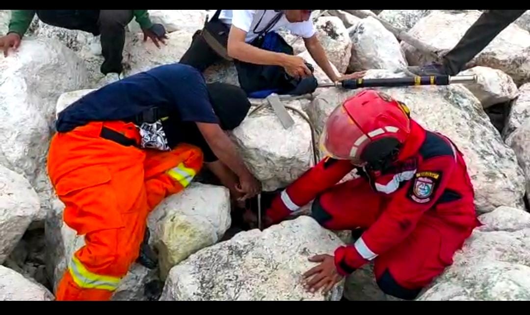 Tim Rescue Pemadam Kebakaran kota Makassar membantu warga kota Makassar mengambil dompet yang jatuh di celah bebatuan kawasan Center Point of Indonesia (CPI).